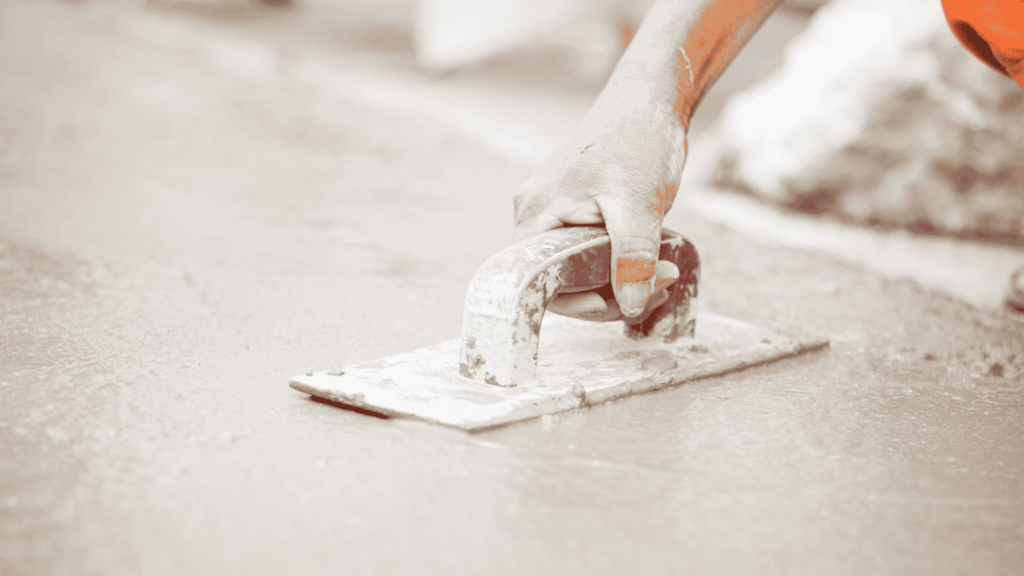 A worker uses a tool to smooth out concrete.