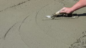 A man uses a trowel to smooth a layer of cement.